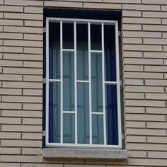 a window on the side of a brick building with bars in it's panes