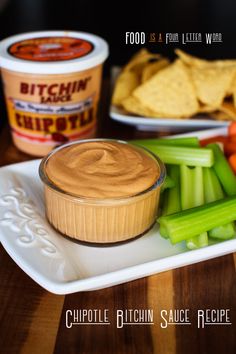 a plate with dip, celery and carrots on it next to chips