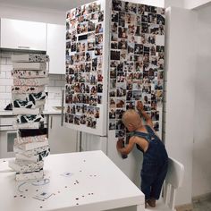 a bald man in overalls leaning up against a wall with pictures on the walls