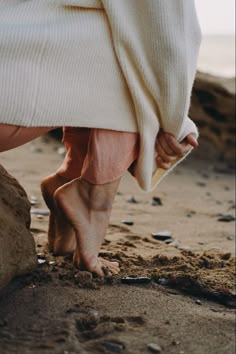 a woman's feet are covered by a blanket on the beach