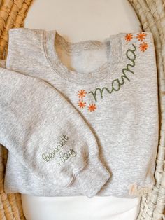 a baby sweater with the word mama on it sitting next to a wicker basket