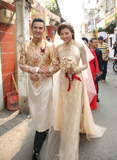 a man and woman standing next to each other in front of some people on the street