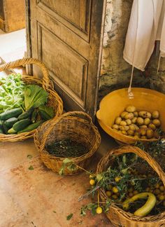 three baskets filled with vegetables sitting on top of a floor next to a wooden door