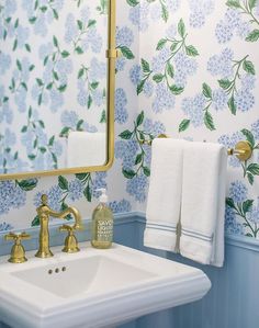 a white sink sitting under a bathroom mirror next to a wall mounted faucet