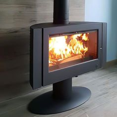 a wood burning stove in a room with wooden floors and walls, showing the fire inside