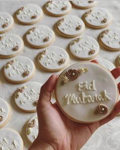 a hand holding a decorated cookie with the words eat muffins written on it