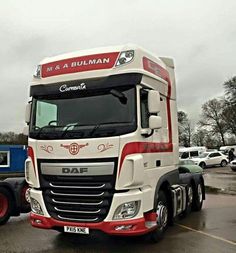 a red and white truck parked in a parking lot next to other cars on a cloudy day