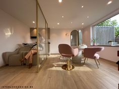 a living room filled with furniture next to a large glass wall window on top of a hard wood floor