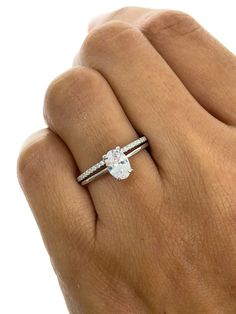 a woman's hand with a diamond ring on her left hand and the other hand holding an engagement ring