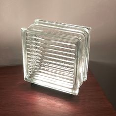 a square glass object sitting on top of a wooden table next to a white wall