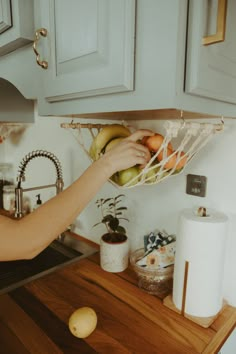 a person reaching for some fruit in the kitchen