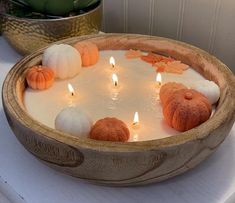 a bowl filled with candles sitting on top of a white table next to a potted plant