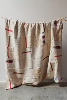 a piece of cloth hanging on a clothes line next to a white wall with red, blue and green stripes