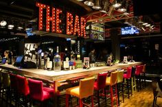 the bar is decorated with neon signs and chairs