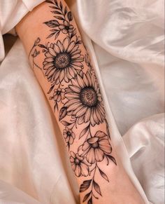 a woman's arm with sunflowers and leaves on it