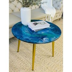 a coffee table with a book and glasses on it in front of a white couch