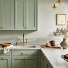 a kitchen with green cabinets and gold pulls on the cupboards is pictured in this image