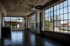 an empty room with large windows and a ceiling fan