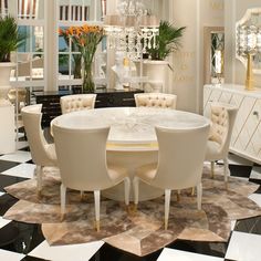 a white dining room table surrounded by chairs and chandelier with flowers in vases