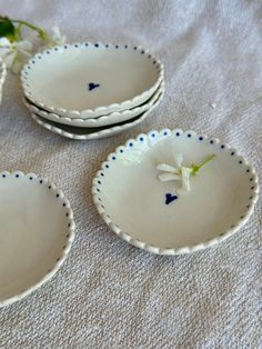 three white bowls with blue trim and flowers in them sitting on a tableclothed surface