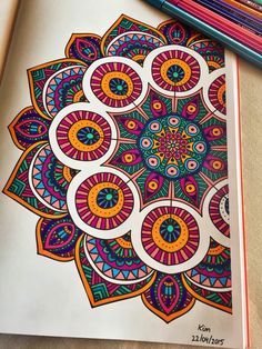 an adult coloring book with colored pencils next to it