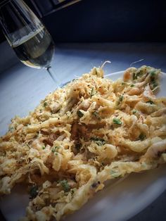 a white plate topped with food next to a glass of wine