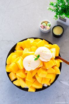 mango and ice cream in a black bowl with text overlay that reads mango bingsu mango shaved ice