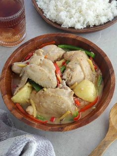 two wooden bowls filled with chicken and vegetables next to rice on top of a table