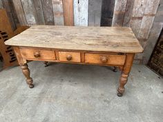 an old wooden table with three drawers