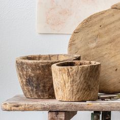 three wooden bowls sitting on top of a table next to a piece of art work