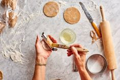 a person is using scissors to cut cookies on a table with dough and rolling pins