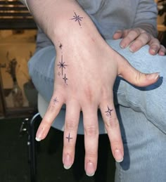 a person's hand with stars tattooed on it