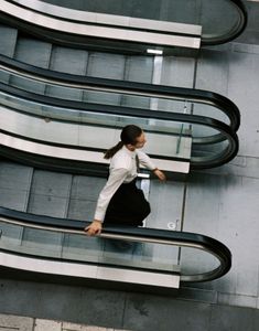 a woman is walking down an escalator