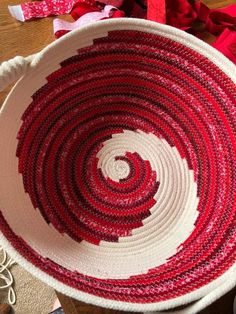 a red and white basket sitting on top of a wooden table next to some scissors