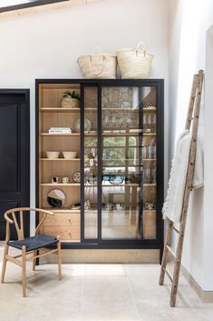 a room with a chair, bookshelf and baskets on top of the shelves