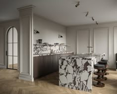 an elegant kitchen with marble counter tops and wooden flooring, along with two bar stools