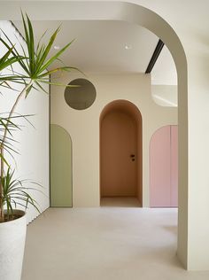 an archway leading to a pink door in a room with white walls and flooring