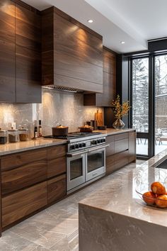 a modern kitchen with stainless steel appliances and wood cabinetry, along with marble counter tops