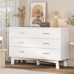 a white dresser sitting in a living room next to a window