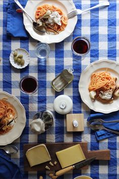 an overhead view of plates of food and utensils on a checkered table cloth