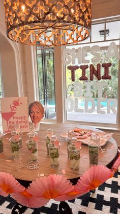 there is a table with many glasses on it and a sign in the background that says happy birthday