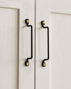 an image of a door handle on the front of a white cabinet with gold knobs