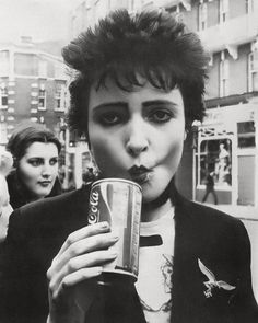 a black and white photo of a woman holding a can of soda in her mouth