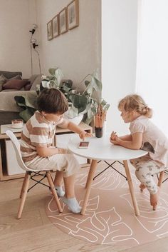 two children sitting at a table playing with toys