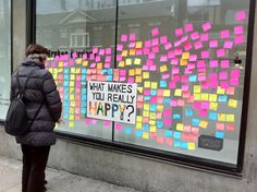 a woman standing in front of a store window with sticky notes on it