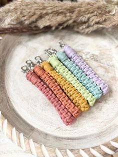 four crochet keychains sitting on top of a white plate next to a pile of feathers