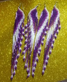 Hand beaded tassel earrings in shades of purple and white. 7 inches long by 1 inch wide.   These are in matte and iridescent beads on silver fish hook ear wires with graduating tassels.  Perfect for any occasion and outfit they're in a bohemian style. Beaded Tassel Earrings, Silver Fish, Purple And White, Beaded Tassels, Boho Stil, Shades Of Purple, Fish Hook, Hand Beading, Tassel Earrings