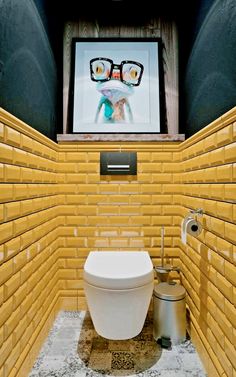 a bathroom with yellow brick walls and a television mounted above the toilet in the corner