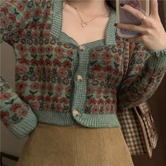 a woman taking a selfie in front of a mirror wearing a sweater and skirt