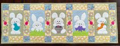 a quilted wall hanging with rabbits and carrots